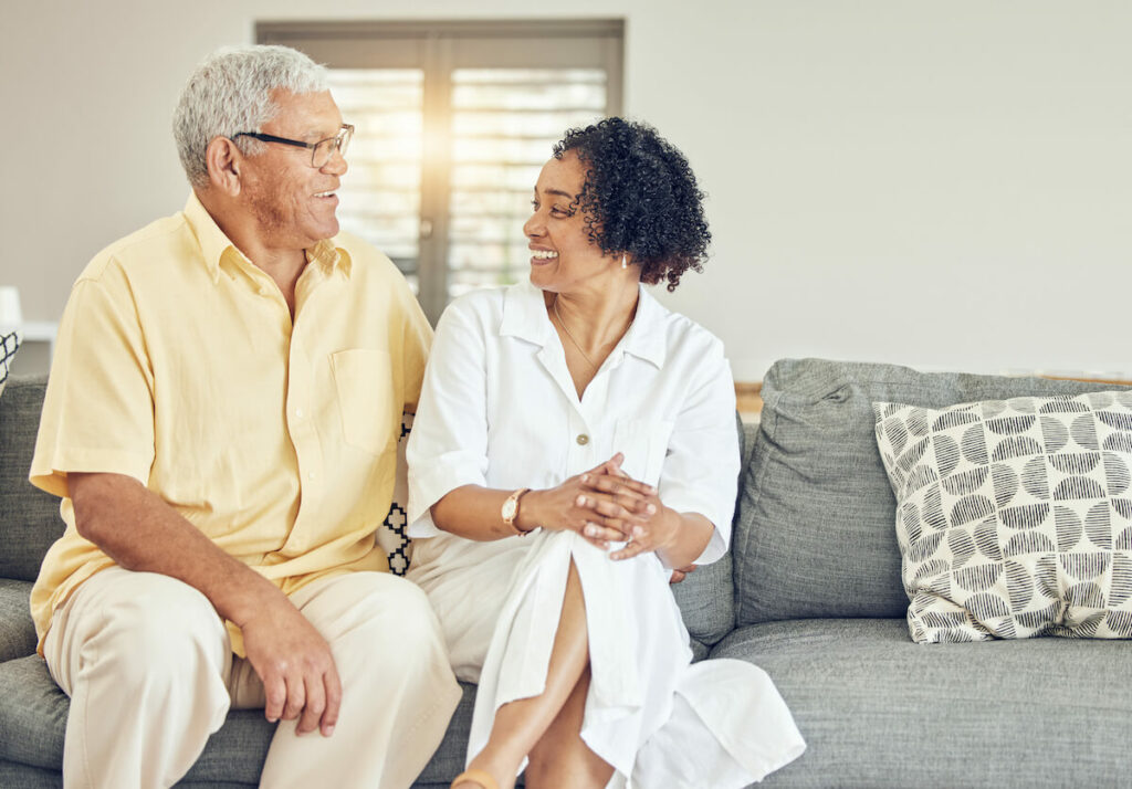 The Gardens | Senior couple looking at each other sitting on their couch