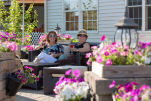 Gardens at Quail Springs | Happy senior ladies sitting in a flower full brick patio.